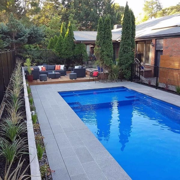 Backyard with a rectangular pool, patio, seating area, and surrounding trees