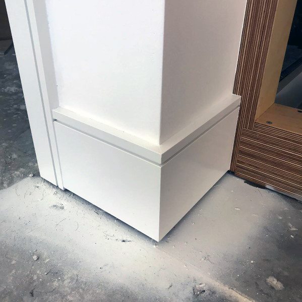White baseboard molding with clean lines and unfinished wood detail nearby.