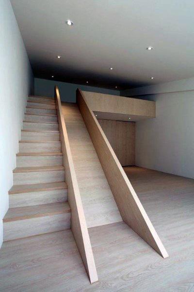 Modern interior with a wooden staircase and matching slide, creating a playful path to the mezzanine level