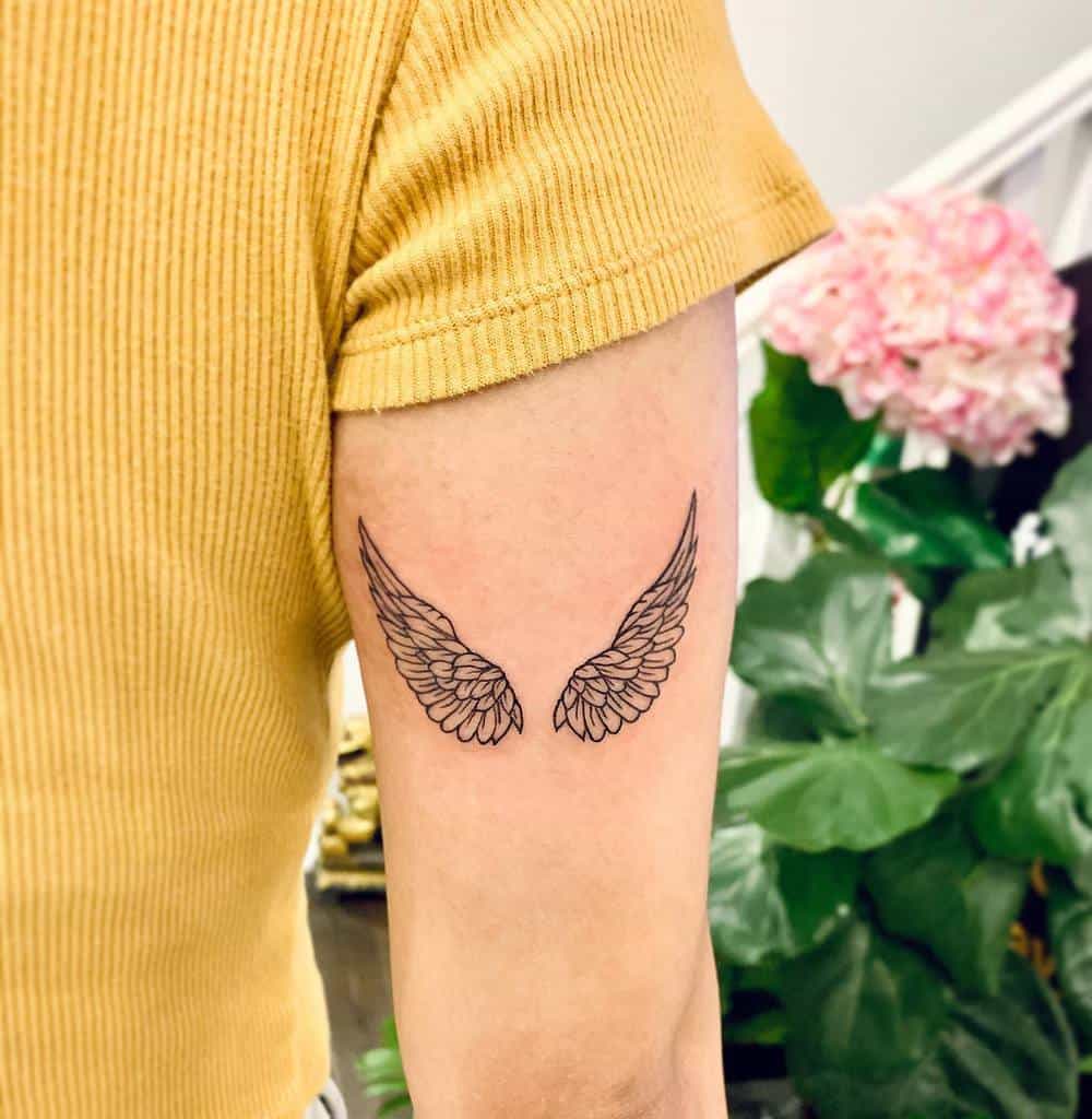 Minimalist angel wings tattoo featuring delicate linework and symmetrical feather details