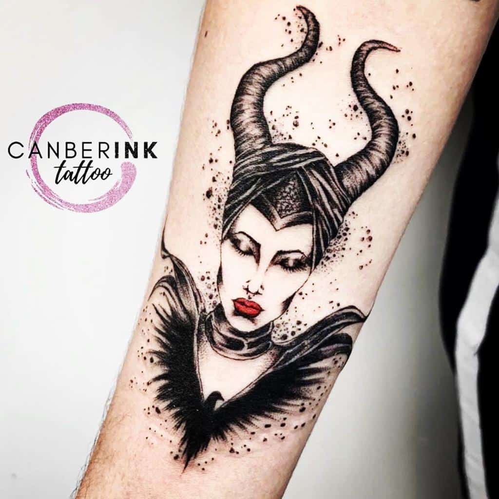 Arm tattoo of a horned Maleficent with red lips and a black bird