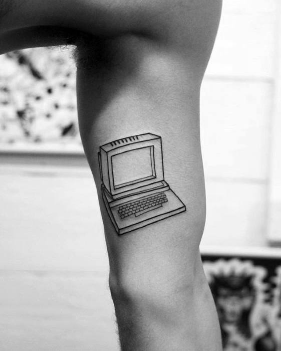 Simple black line tattoo of a vintage desktop computer with a blank screen and keyboard, placed on the back of the thigh.