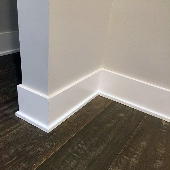 White baseboard molding on light walls with dark hardwood flooring.