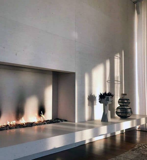 Modern minimalist fireplace with concrete surround, decorative vases, and soft natural light.