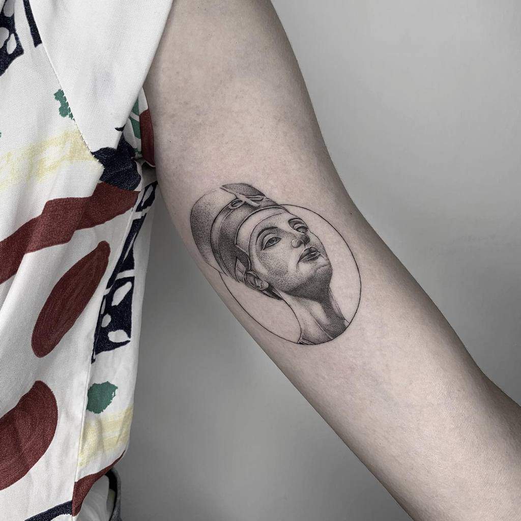 Arm tattoo depicting an ancient Egyptian Nefertiti-style face with a headdress