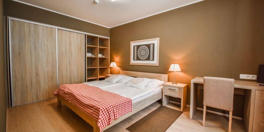 Cozy bedroom with double bed, large wardrobe, desk, and warm lighting.