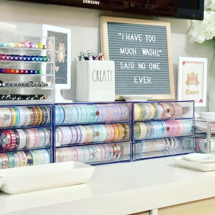 A neatly arranged crafting station with washi tape, a decorative sign, and storage containers on a desk