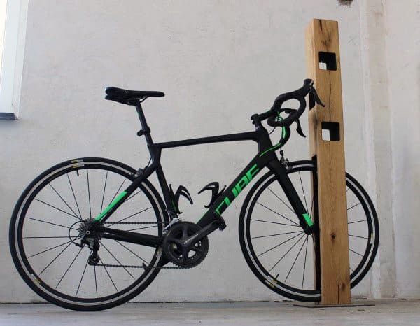 Minimalist wooden post bike stand for simple and stylish bicycle storage.