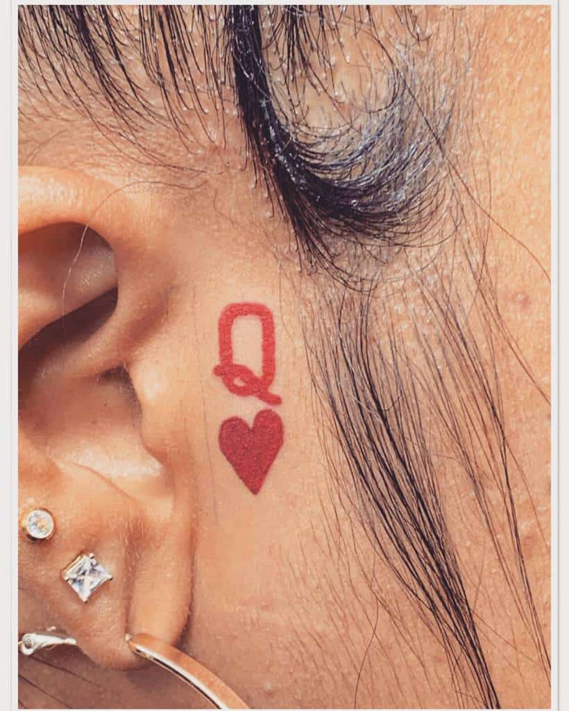 Minimalist red Queen of Hearts tattoo featuring a simple yet bold 'Q' and heart symbol for a subtle, regal touch