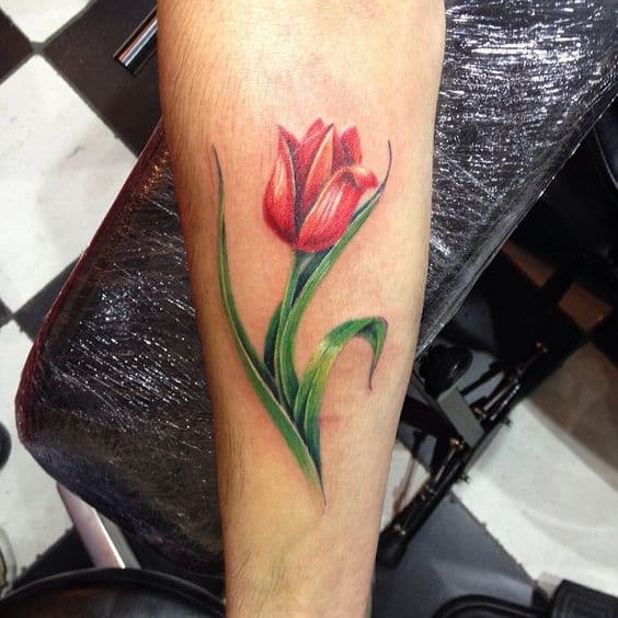 A colorful tulip tattoo on the forearm, featuring vibrant red petals, green leaves, and detailed shading for a realistic look.