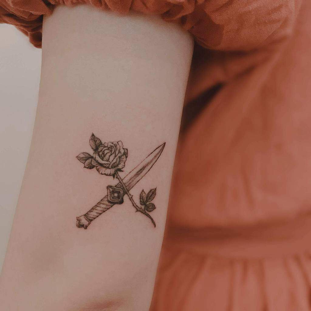 Tattoo of a dagger and a rose on an arm