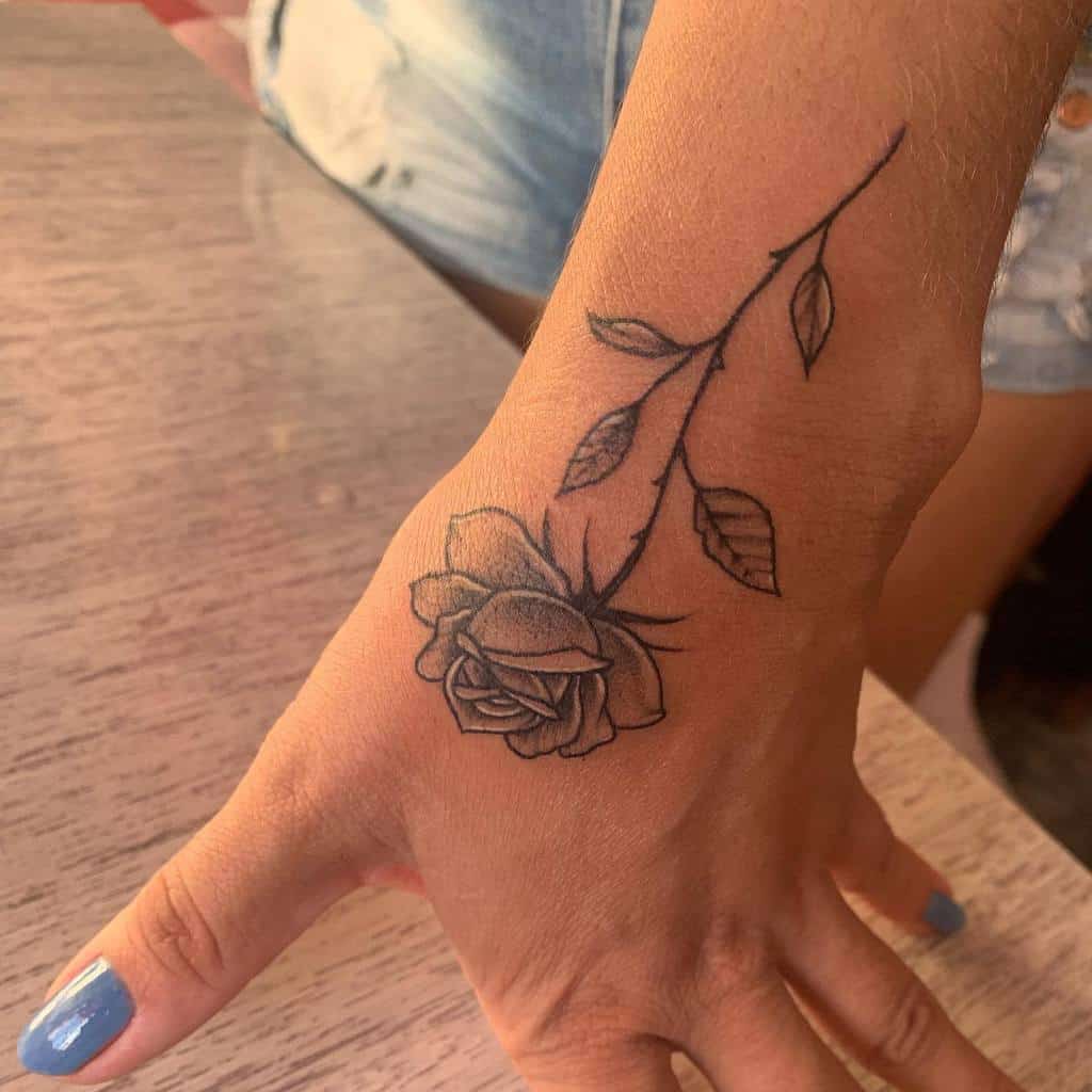 A delicate tattoo of a blooming rose gracefully adorns the hand