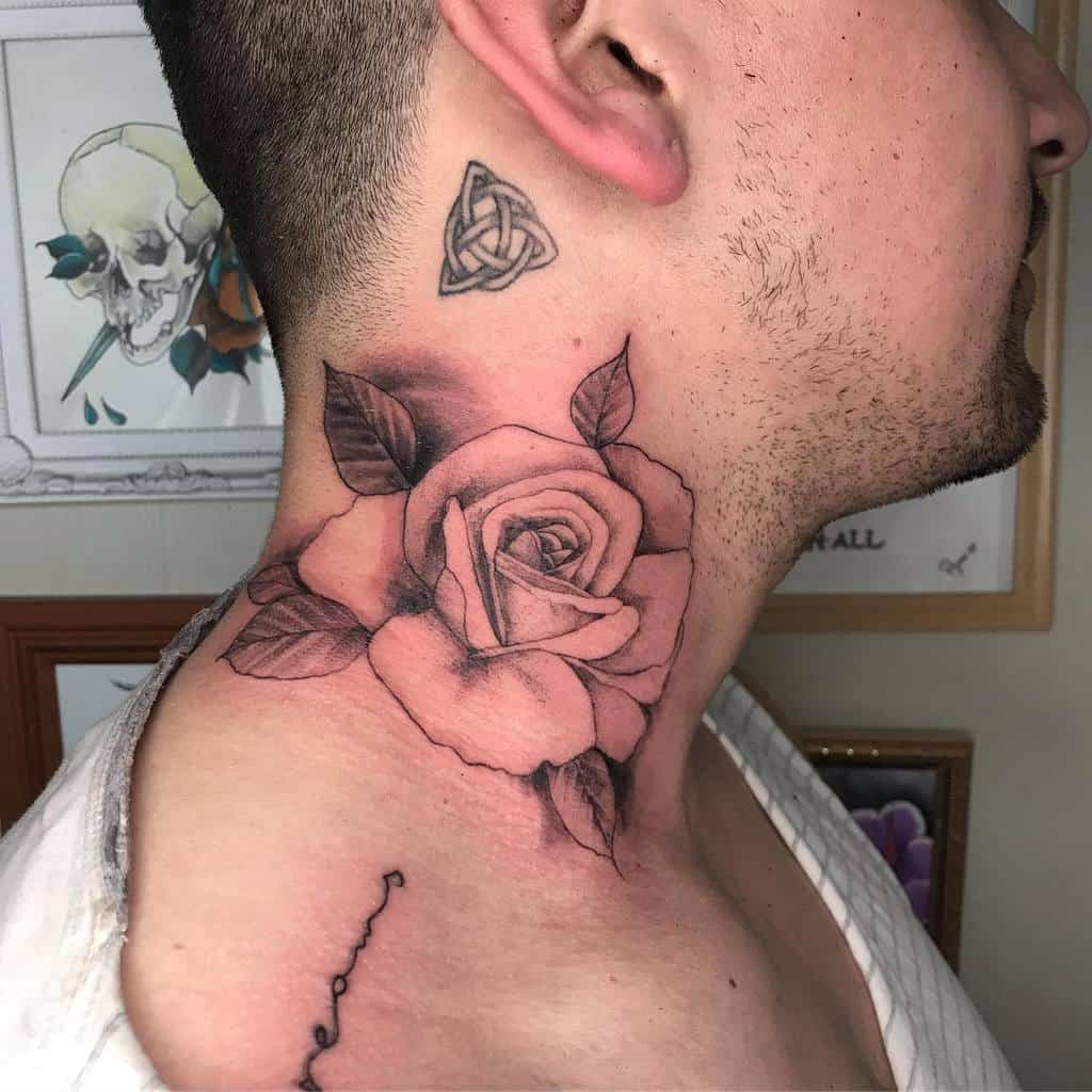 Delicate black and grey rose tattoo on the neck with soft shading, detailed petals, and bold leaves for an elegant design