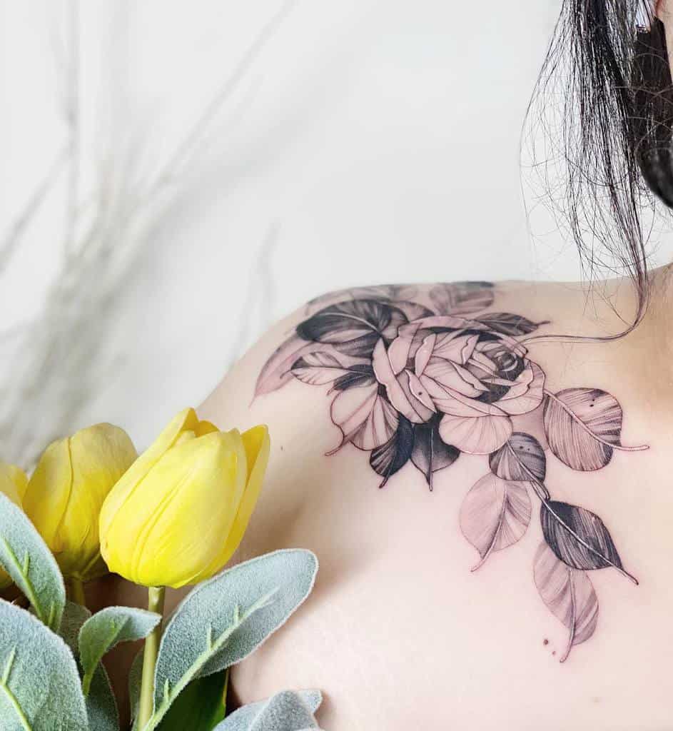 A stunning floral tattoo gracefully adorns the shoulder, featuring vibrant yellow tulips prominently in the foreground