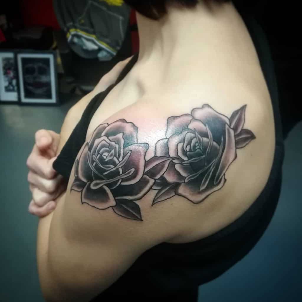 A beautifully intricate tattoo of two shaded roses graces the shoulder, blending elegance with artistry