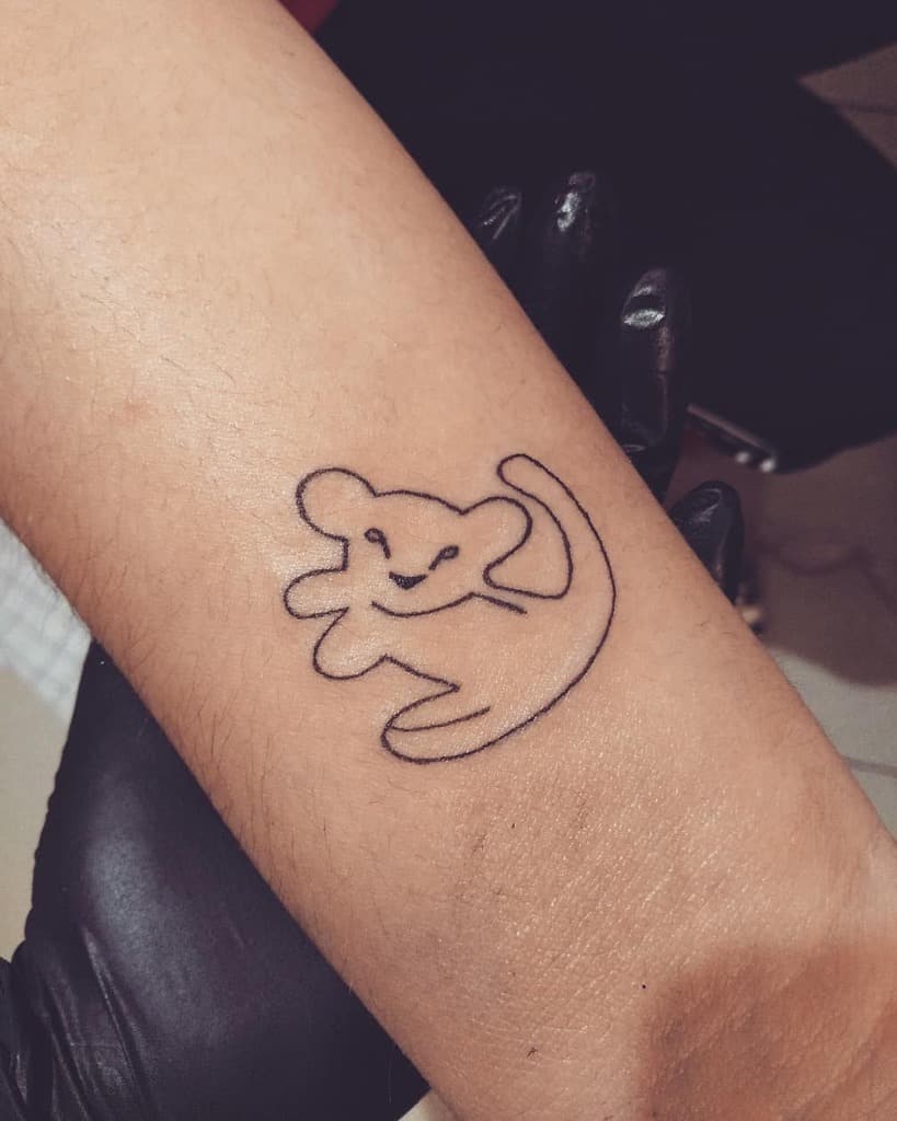 Minimalist line tattoo of Simba as a cub, capturing his playful and joyful spirit with a simple outline design