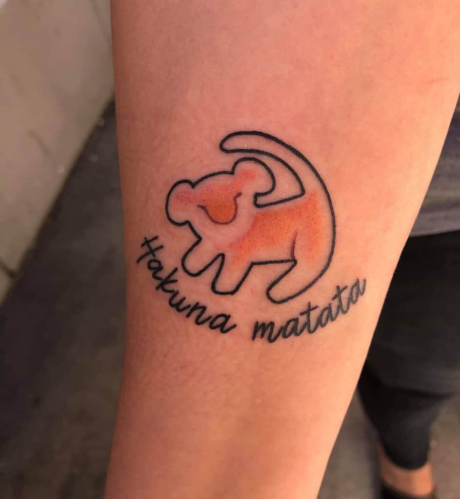 Tattoo of a stylized orange Simba with the phrase "Hakuna Matata" written below it