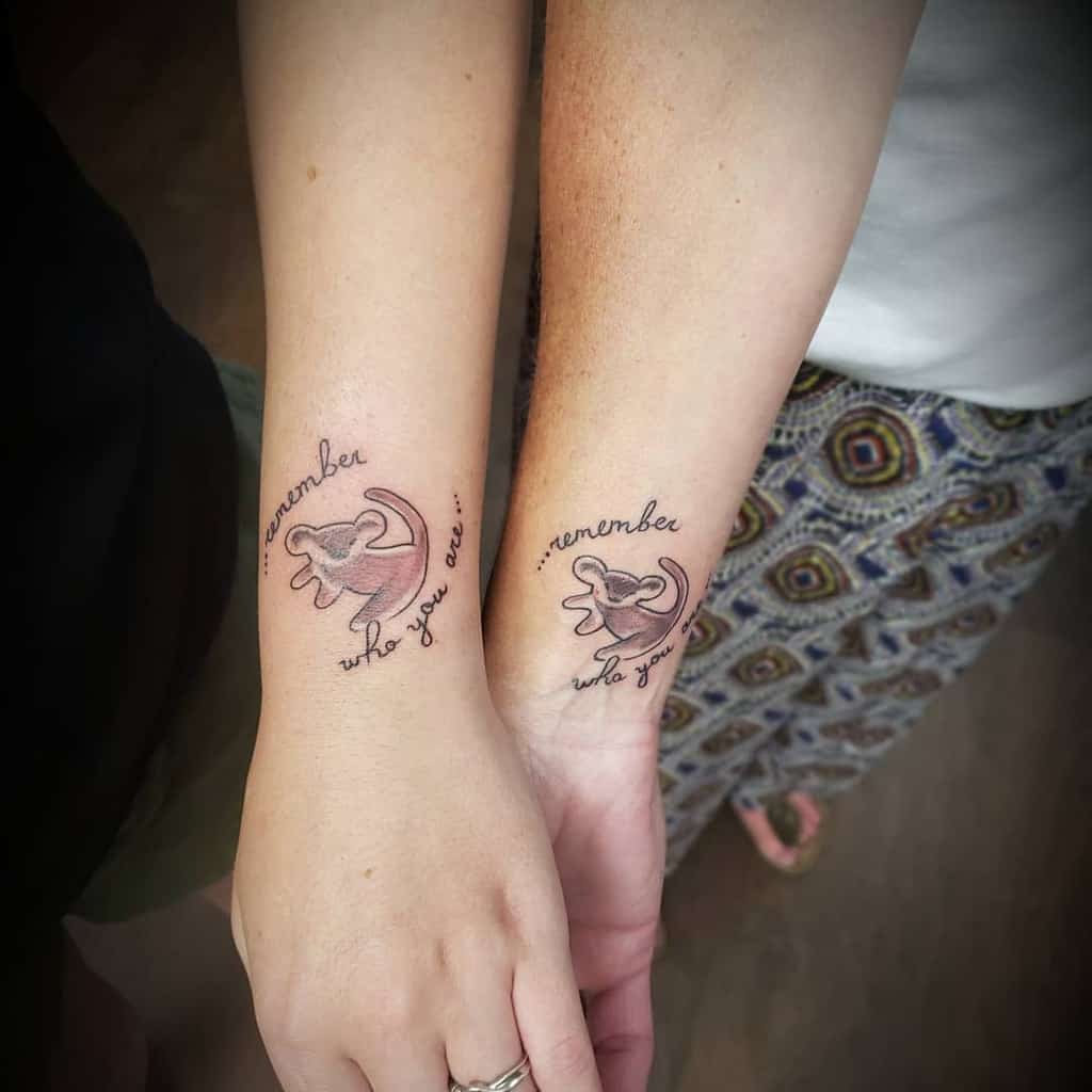 Two forearm Simba as a lion cub tattoos featuring a stylized design with the phrase "remember who you are" above and below the image