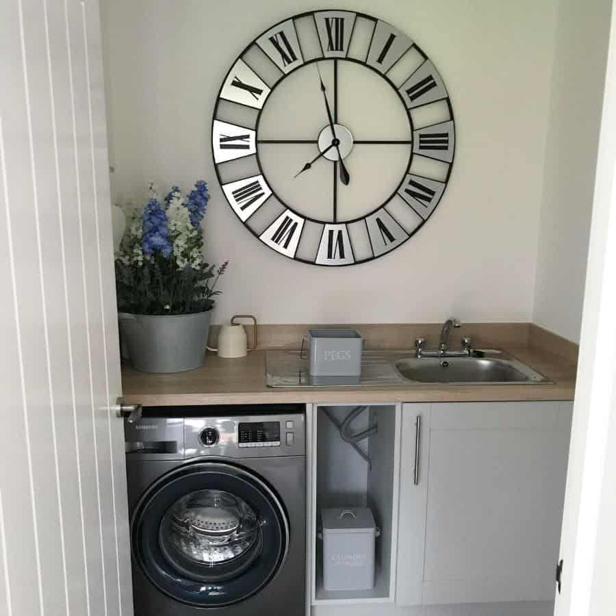 washer under sink in small laundry with large wall clock