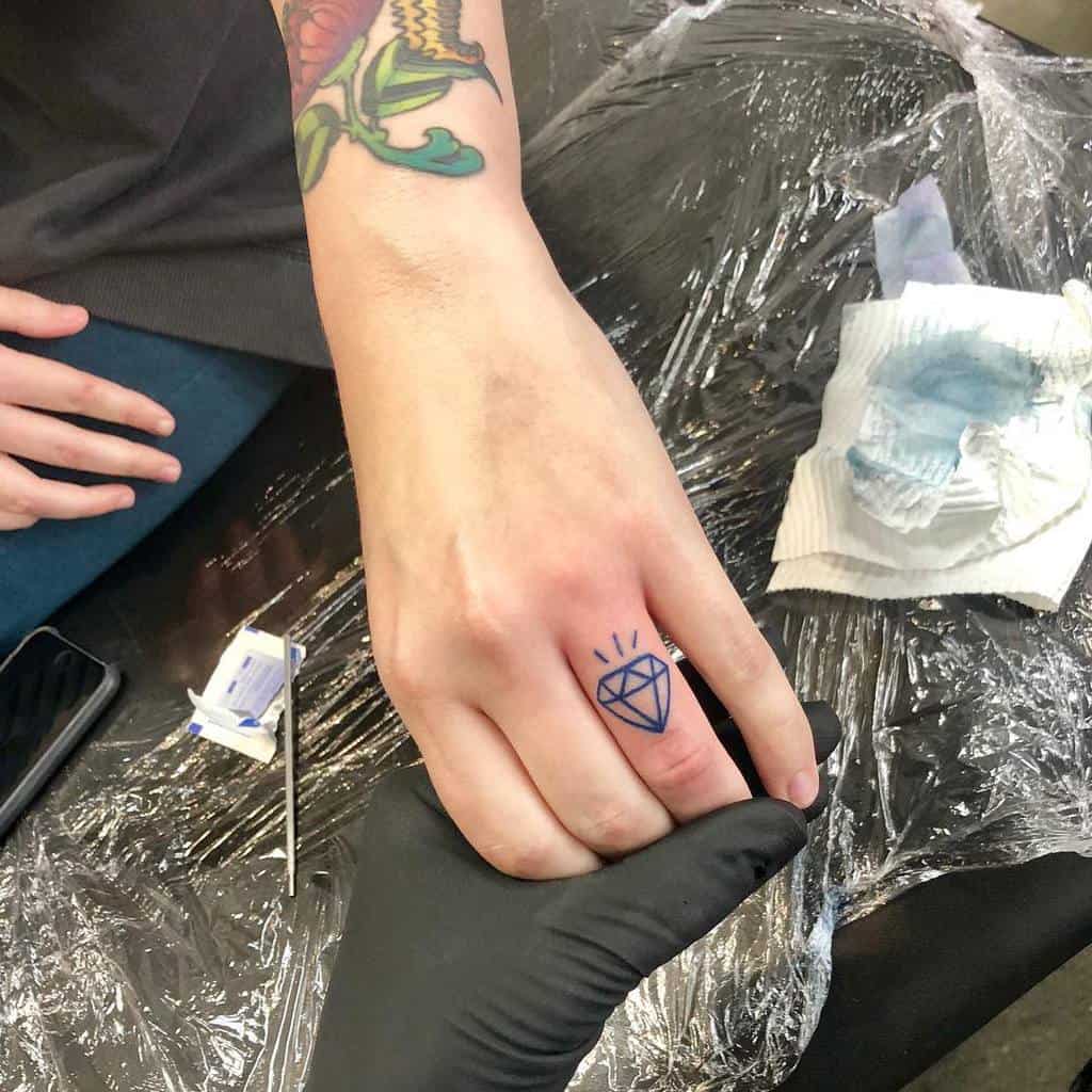 A hand with a newly inked wedding ring tattoo of a simple diamond design, symbolizing love and commitment