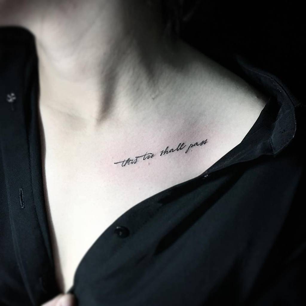 A "This Too Shall Pass" tattoo in cursive on the upper chest.