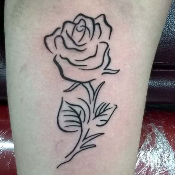 Line art tattoo of a rose with a stem and leaves on skin