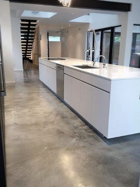 Modern kitchen with sleek white cabinets, stainless steel appliances, and chic concrete floors