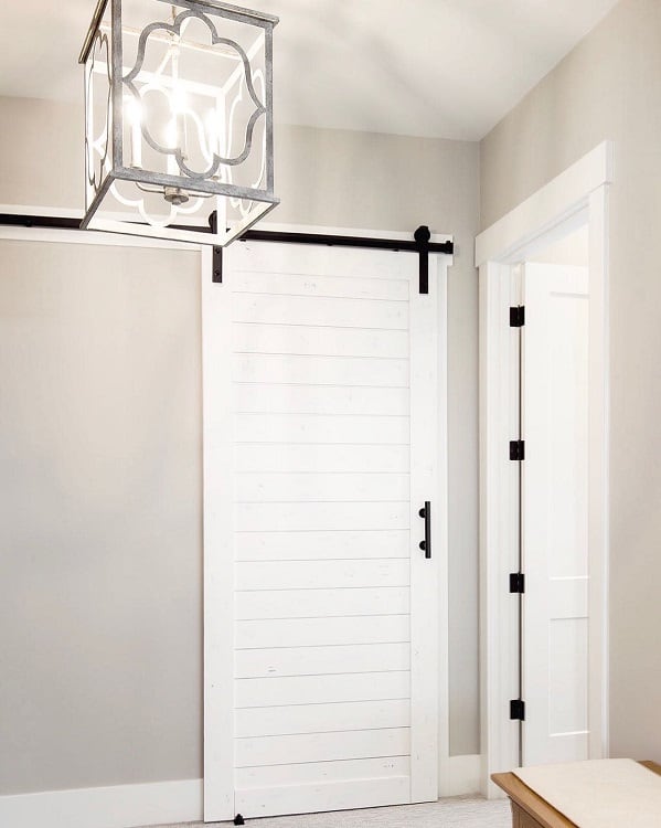White sliding barn door with black hardware in a minimalist hallway leading to a closet.
