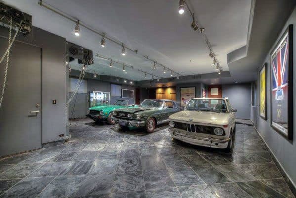Classic car garage with slate tile flooring, gray walls, and track lighting on the ceiling.