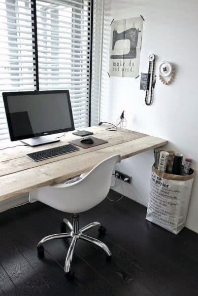 Minimalist home office with a wooden desk, computer, white chair, and wall decor