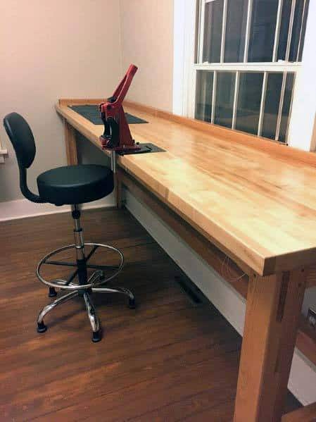 Minimalist and functional reloading bench setup with a long wooden workspace, ergonomic stool, and a single reloading press, perfect for streamlined precision and organization