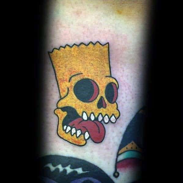 Bold tattoo of Bart Simpson’s skull with sharp teeth, hollow eyes, and a protruding tongue, blending cartoon and gothic styles.