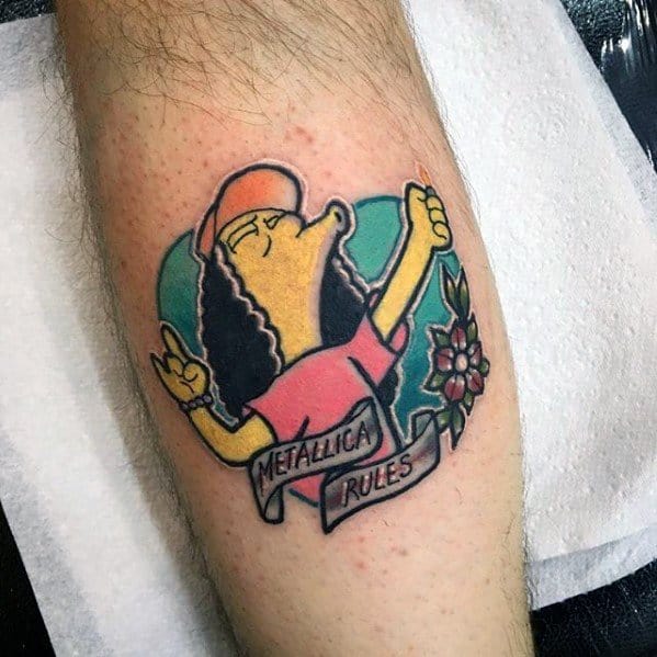 Colorful cartoon-style tattoo of Otto from The Simpsons throwing metal horns, with a banner reading Metallica Rules and a floral accent.