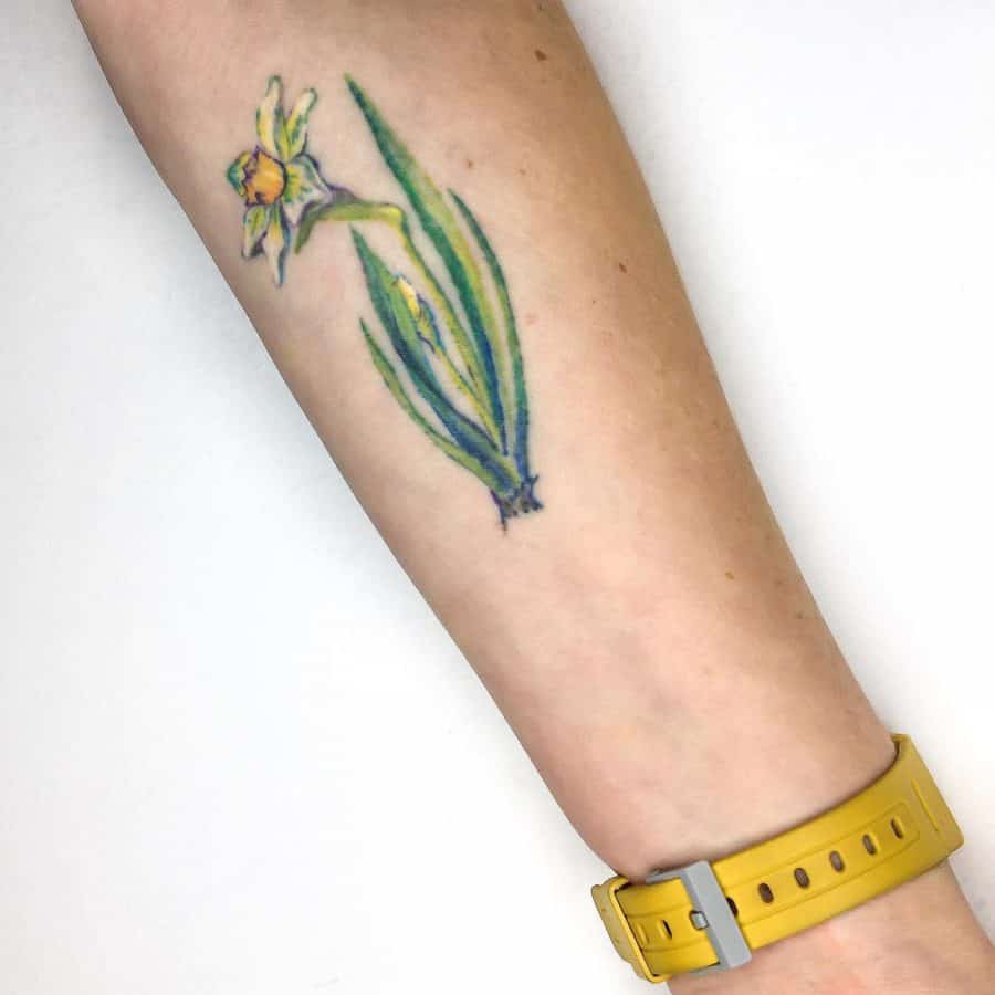 A colorful tattoo of a daffodil, featuring bright yellow petals and vibrant green leaves, capturing a fresh and lively floral design.
