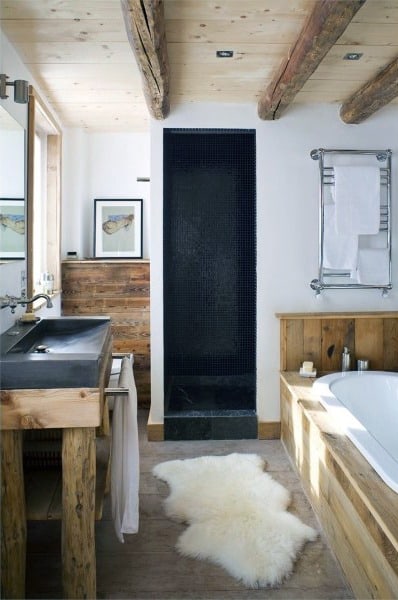 Rustic bathroom with wooden beams, black shower, and a plush white rug