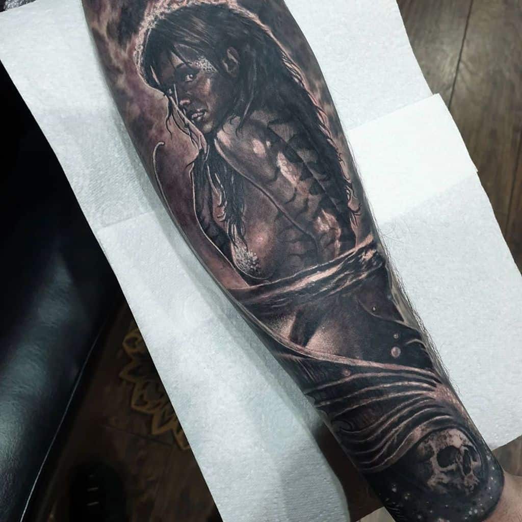 Dark realism tattoo of a mysterious mermaid with detailed shading, eerie lighting, and skeletal elements, creating a haunting underwater theme.