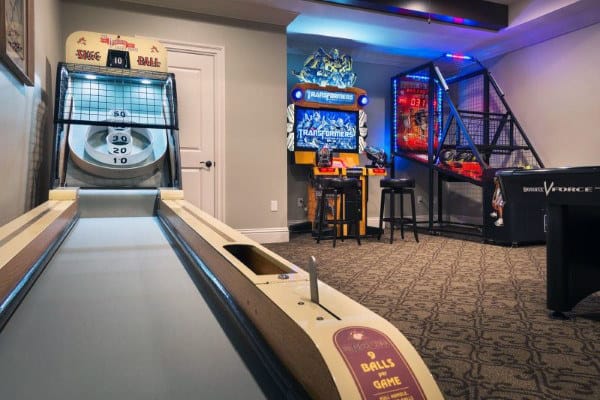 A home game room with arcade games, a skee-ball machine, and a basketball hoop game