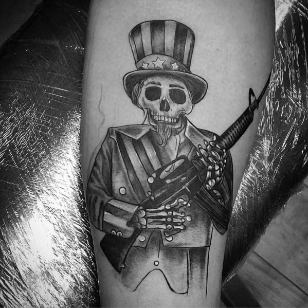Black and grey tattoo of a skeletal Uncle Sam holding an AR-15, symbolizing patriotism, rebellion, and the right to bear arms with a bold design.