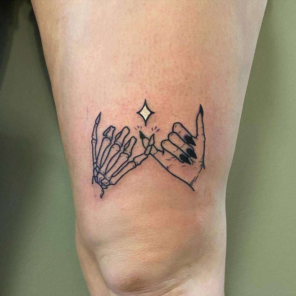 Tattoo of a skeleton hand and a human hand making a pinky promise, with a small star above, on a leg above knee