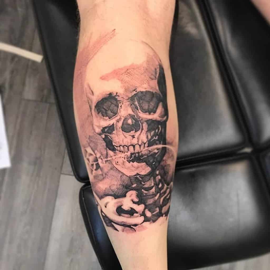 Realistic black and grey skull tattoo on calf with shaded details and subtle rose elements for a bold, gothic look.