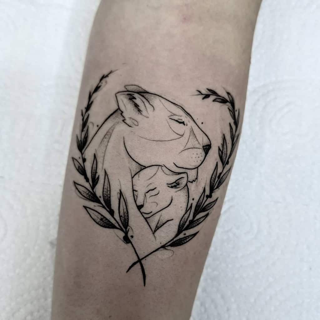 Minimalist black linework tattoo of a lioness and cub in an embrace, framed by delicate laurel branches, symbolizing love and protection.