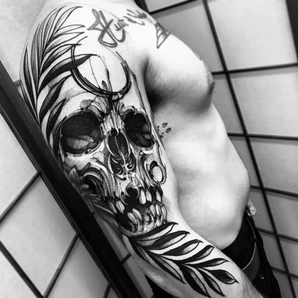 Black and grey full-sleeve tattoo featuring a bold abstract skull design with brushstroke effects and detailed leaves for a striking artistic look.