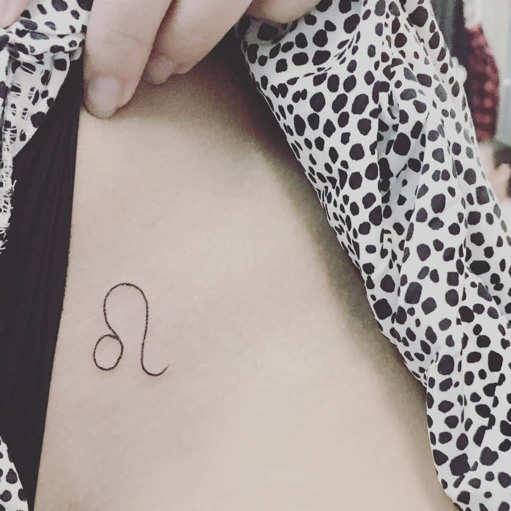 Small and stylish Leo glyph tattoo on the ribcage, subtly revealed under a patterned shirt.