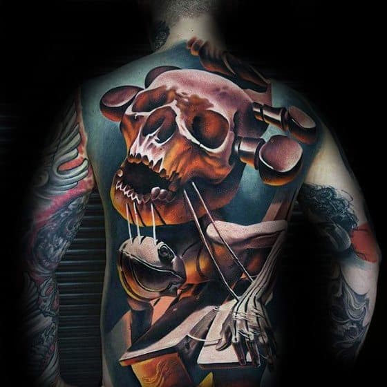 Person with a detailed, colorful skull and puppet-themed back tattoo