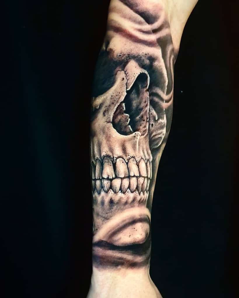 Detailed skull tattoo on an arm, featuring realistic shading and swirling patterns around the skull
