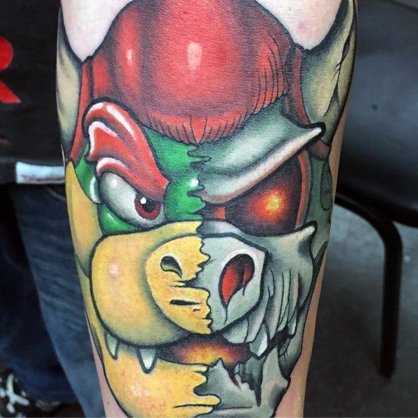 Unique Bowser and Dry Bowser split-face tattoo on a man's arm featuring bold colors, sharp details, and a striking half-living, half-skeletal design.