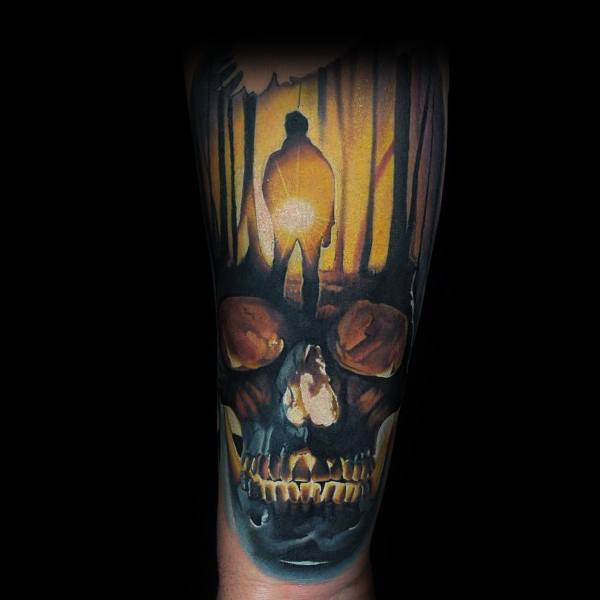 Dark forest tattoo featuring a silhouette figure and glowing light, forming a skull with haunting eyes and fiery tones.