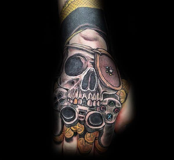 Colorful tattoo of a pirate skull with an eye patch holding a video game controller, surrounded by gold coins, blending gaming and pirate themes.