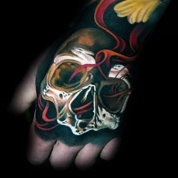 Vibrant hand tattoo of a skull wrapped in red ribbons with a touch of yellow, symbolizing mortality, passion, and the cycle of life.