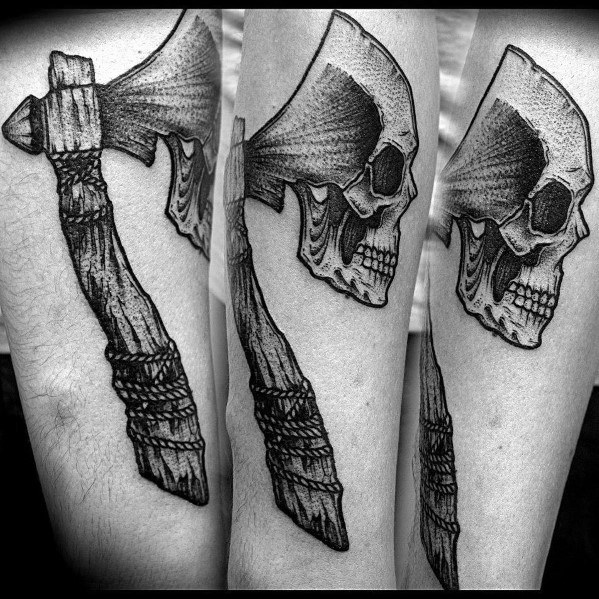Black and grey hatchet tattoo with a detailed skull integrated into the blade, a wrapped handle, and bold shading for a dark and rugged look.